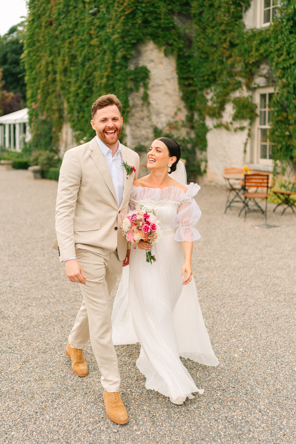 Bride and groom walk along the pathway to venue courtyard