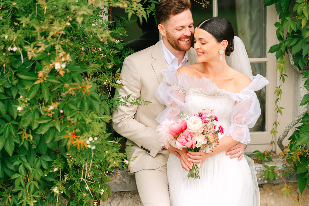 Bride and groom lean against bricked wall and smile