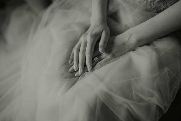 Black and white image of brides hands on her bridal gown material