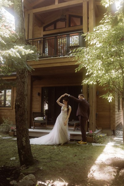 Groom swings and swirls his bride around in dance form exterior shot