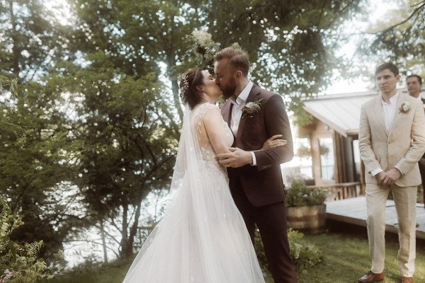 Bride and groom kissing outside in forest tree setting