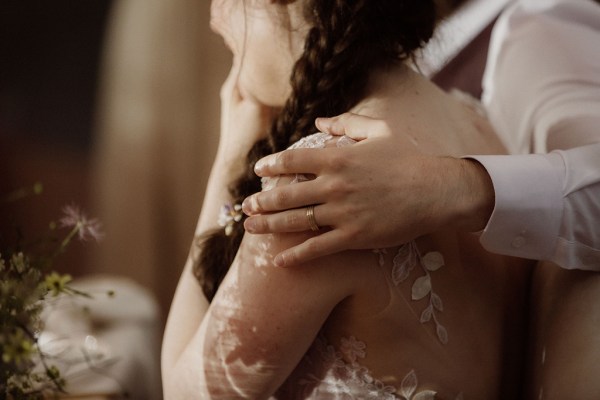 Groom has his arms around brides shoulders hug embrace