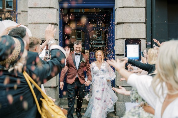 Guests taking pictures of bride and groom outside wedding venue