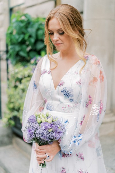 Bride holding purple bouquet floral wedding dress bride looks down