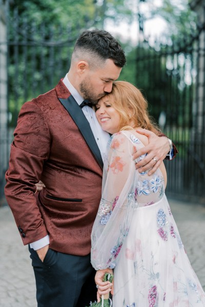 Groom kisses bride on brides forehead outside exterior shot