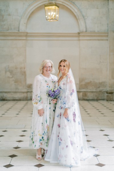 Bride and mother hug purple bouquet flowers