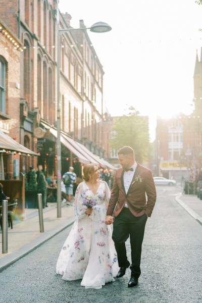 Bride and groom walking hand in hand down an Irish street road