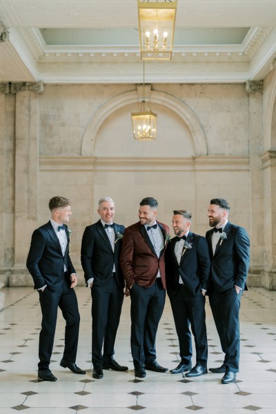 Groom and groomsmen walk on the white and black tiled floor