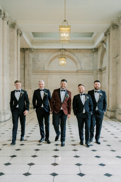 Groom and groomsmen walk on the white and black tiled floor