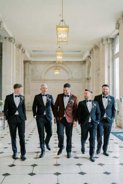 Groom and groomsmen walk on the white and black tiled floor