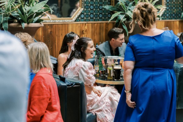 Mother in blue dress stands beside table with women