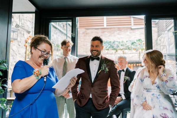 Mother in blue dress reading speech out to groom and guests