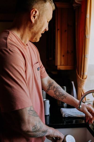 Groom tattooed arm standing at the kitchen sink