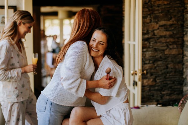 Bride and bridesmaid hug smiling