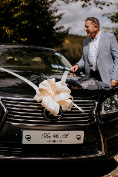 Wedding car white bow at front and father