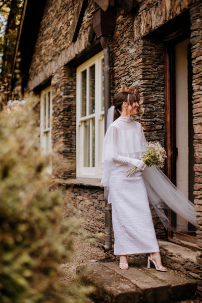 Bride exits house holding bouquet walking down the steps