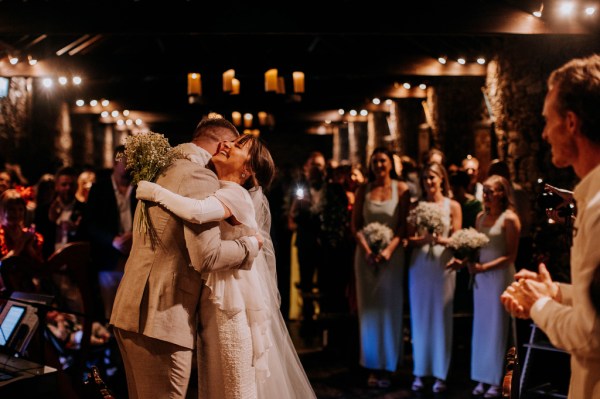 Bride and groom hug bridesmaids stand in background