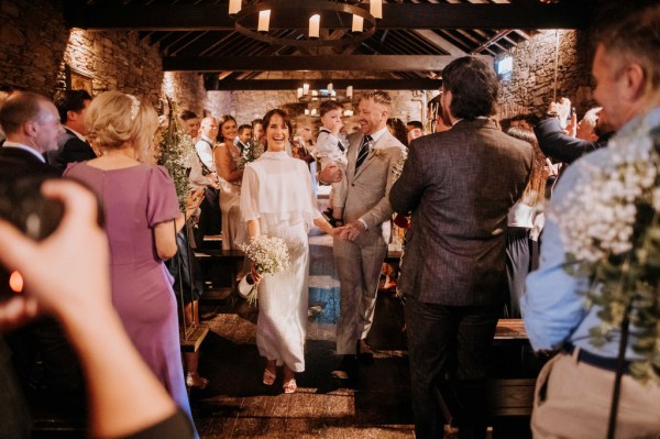 Nighttime shot of bride and groom surrounded by candles clapping guests