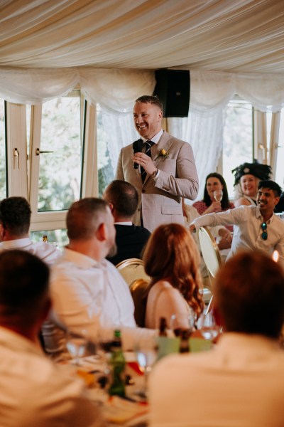 Groomsman giving speech in ballroom