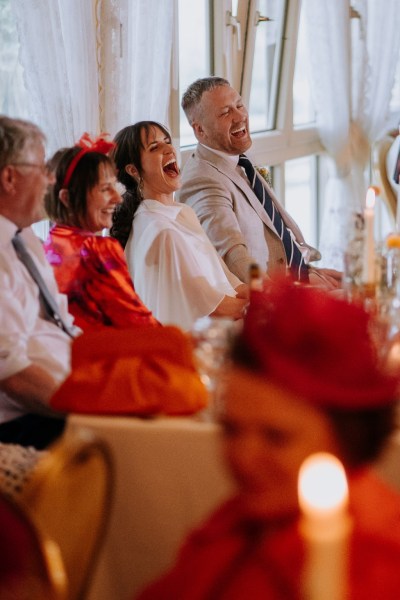 Bride groom mother father laughing during speeches