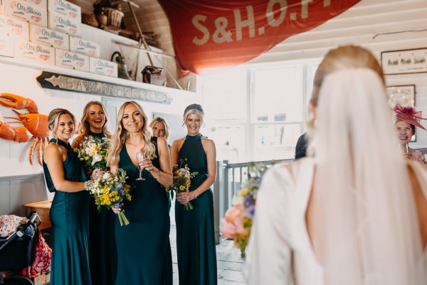 Bridesmaids smiling as they see bride veil detail