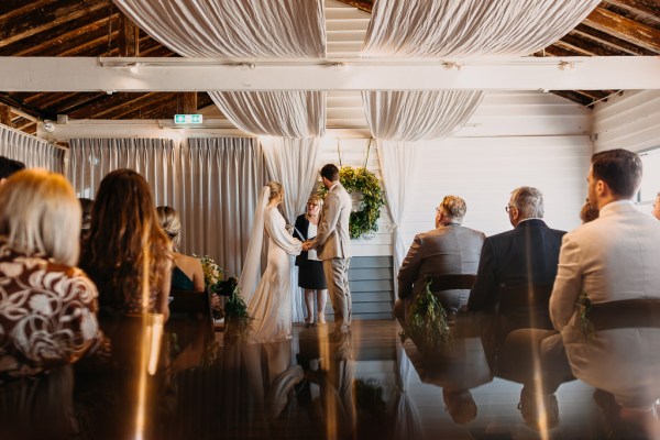 Bride and groom stand holding hands at alter