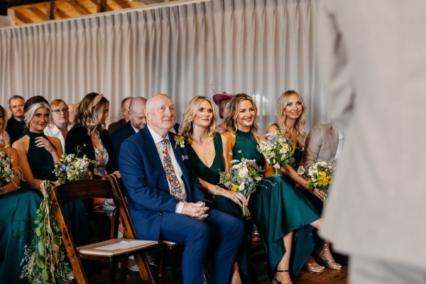 Bridesmaids sit in front row smiling with father seated