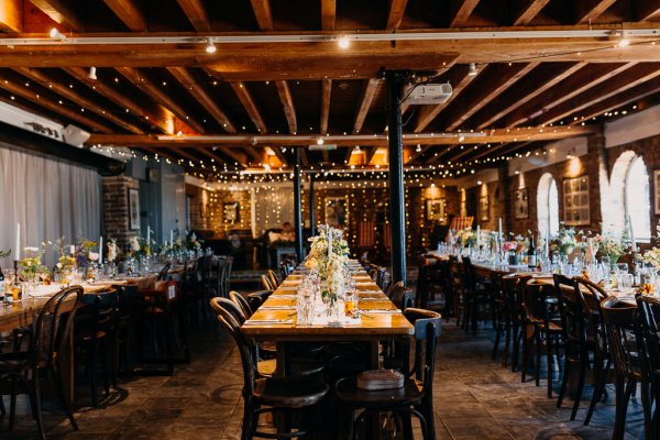 Wedding reception wooden tables with vases full of colourful flowers