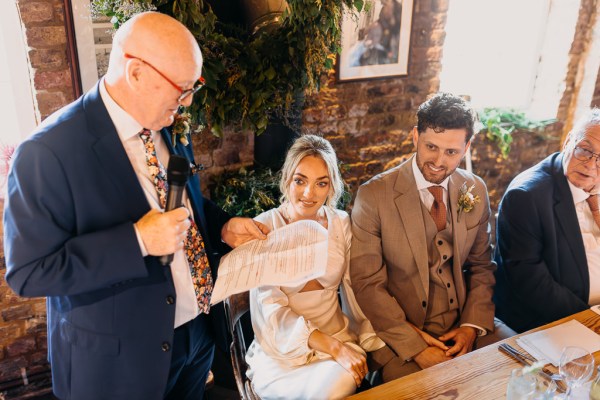 Father of the bride reading speech beside newlyweds