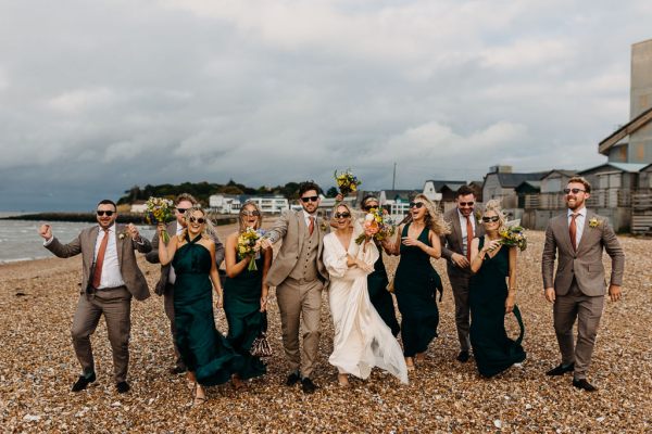 Bride groom bridesmaids groomsmen celebrate wedding on the beach sand rocks and sea