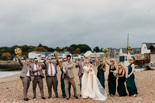 Bride groom bridesmaids groomsmen celebrate wedding on the beach sand rocks and sea