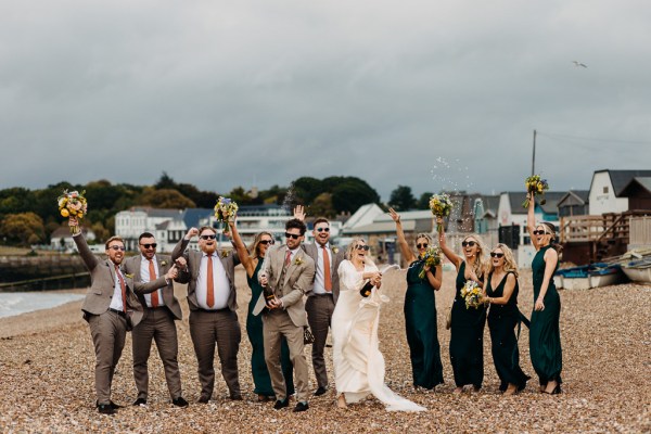 Bride groom bridesmaids groomsmen celebrate wedding on the beach sand rocks and sea