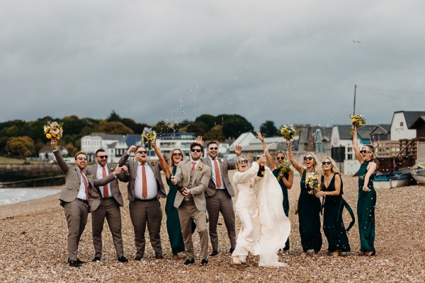 Bride groom bridesmaids groomsmen celebrate wedding on the beach sand rocks and sea