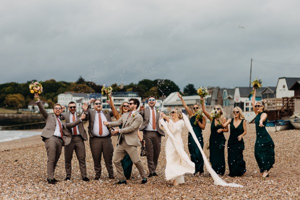 Bride groom bridesmaids groomsmen celebrate wedding on the beach sand rocks and sea