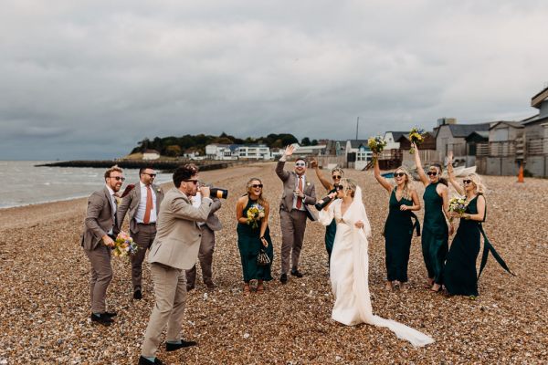 Bride groom bridesmaids groomsmen celebrate wedding on the beach sand rocks and sea