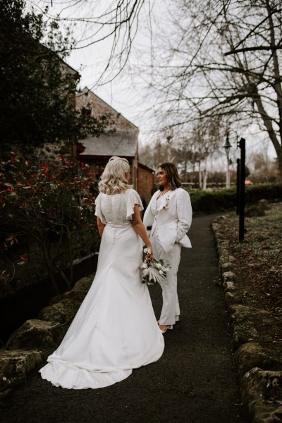 Brides walk down pathway in garden