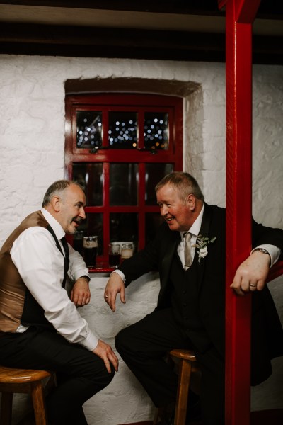 Two men laughing drinking on stools