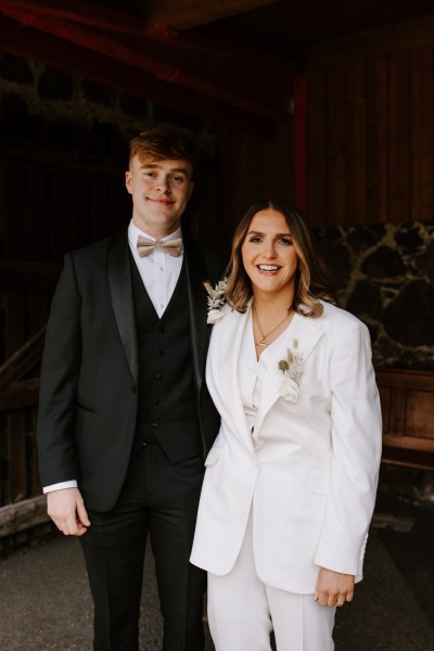 Bride and brother/groomsman smile pose for a picture