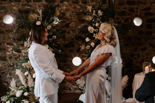 Brides hold hands during ceremony