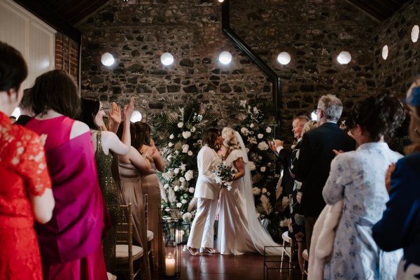 Brides kiss at the alter in front of guests