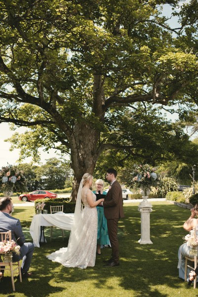 Bride and groom at top of alter during ceremony standing in front of guests with celebrant