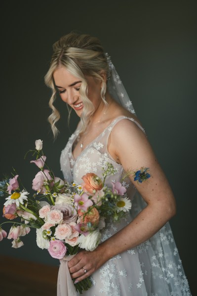 Bride holds flowers bouquet and looks down smiling