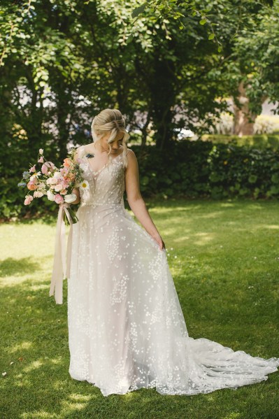 Bride stands on her own in garden