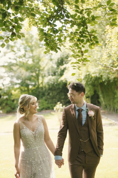 Bride and groom holding hands in garden