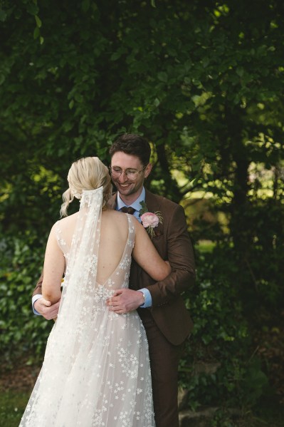 Bride and groom hugging each other veil from behind