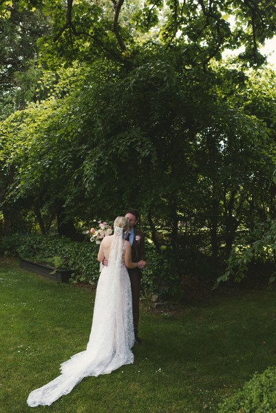 Bride and groom hugging each other veil from behind