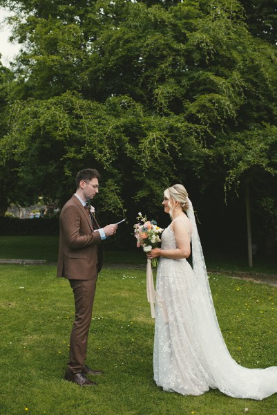 Bride and groom stand in the garden together they read their vows