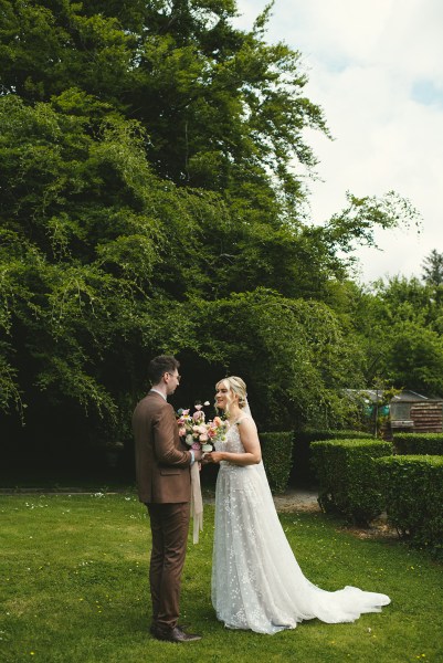 Bride and groom stand in the garden together they read their vows