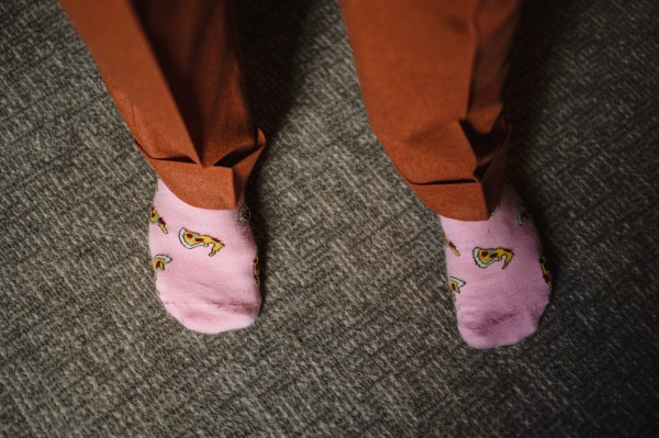 Groom in orange suit getting ready pink socks in view