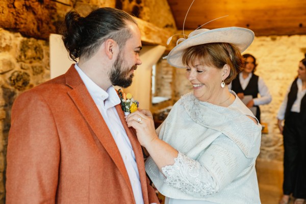 Groom in orange suit and mother getting ready